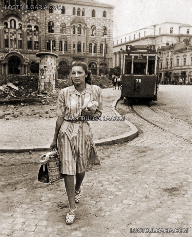 София 1944 г,. млада жена прекосява площада пред сградата на Духовната академия, отзад трамвай номер 4 и Съдебната палата